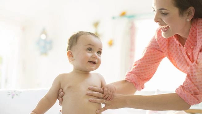 Mamá sonriente sosteniendo a su bebé feliz