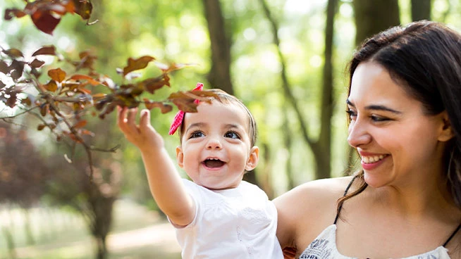 Madre sonriendo mientras sostiene a su hija feliz