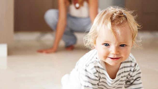 Toddler crawling with mom behind