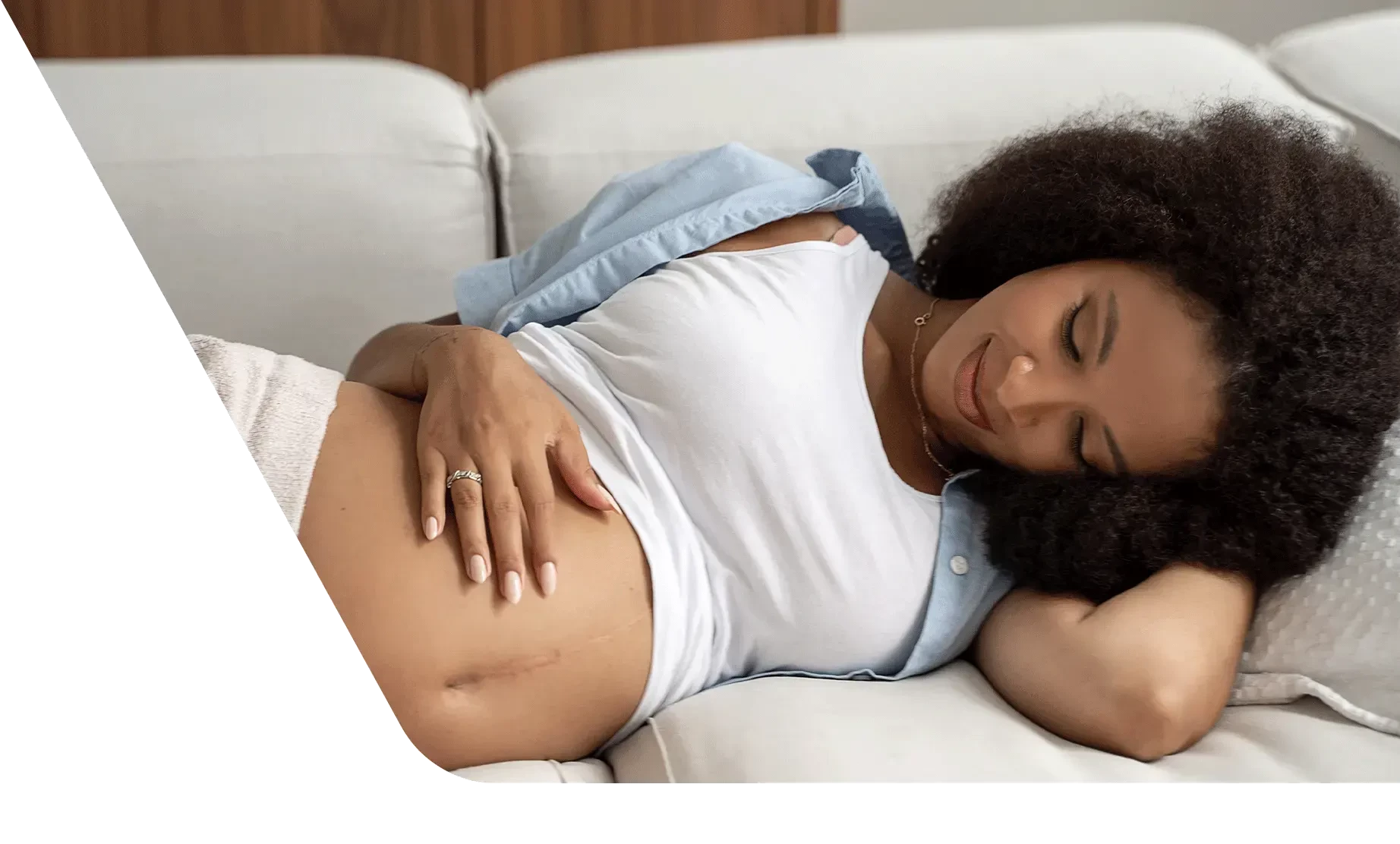 Pregnant woman laying on couch holding belly