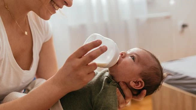 Mom smiling and feeding new baby