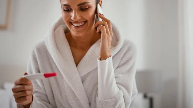 Woman in a bathrobe looking at pregnancy test