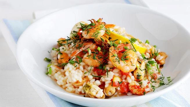 Close up of a bowl of risotto with shrimp, peas, and fennel