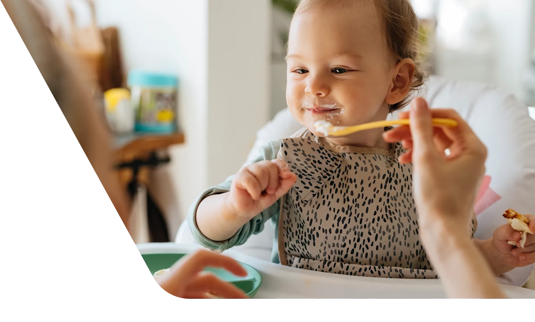 Mom feeding little girl food with a spoon