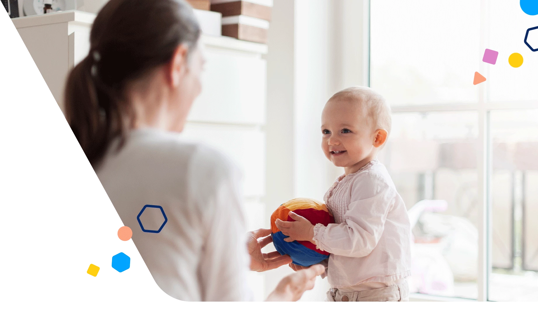 Toddler holding beach ball toy and looking at mom