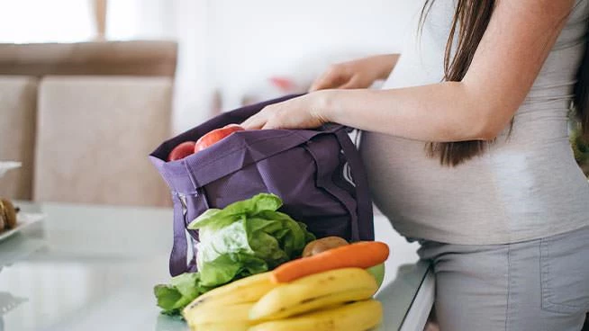 Expecting mom unpacking her grocery bag