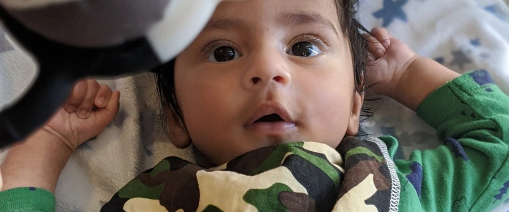 Baby lying on his back looking up at a toy