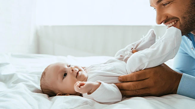 Papá jugando con el bebé en la cama