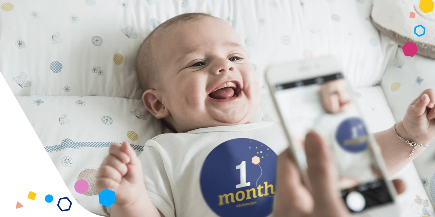 Padre tomando una fotografía de un bebé con Belly Badge™ de 1 mes