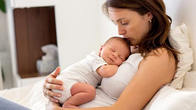 Mom sitting and holding her newborn against her chest