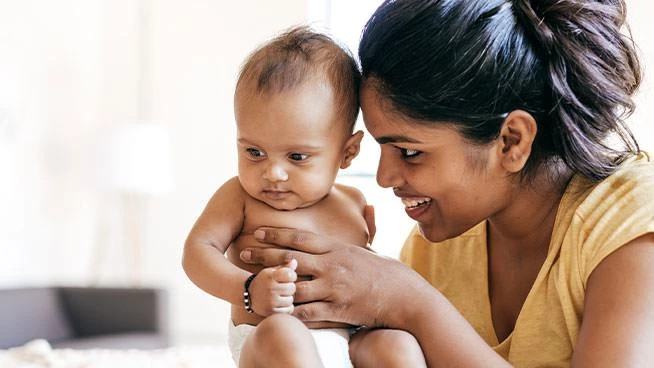 Mes sonriendo y sosteniendo a un bebé de 6 meses