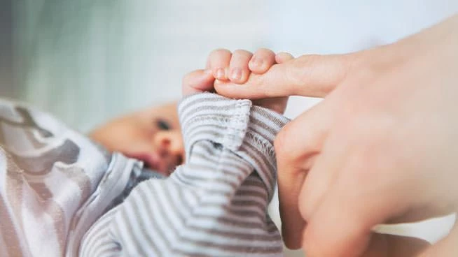 Baby grasping mom's finger