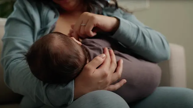 Mom sitting in a chair breast feeding her baby