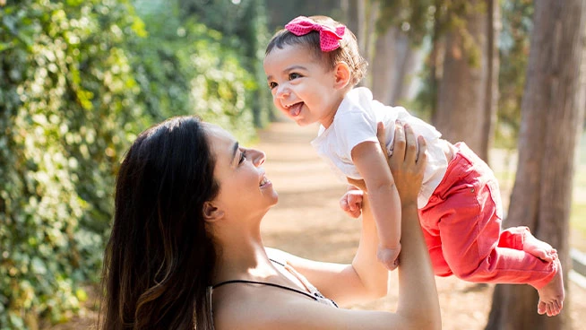 Mamá sosteniendo a su hija en el aire