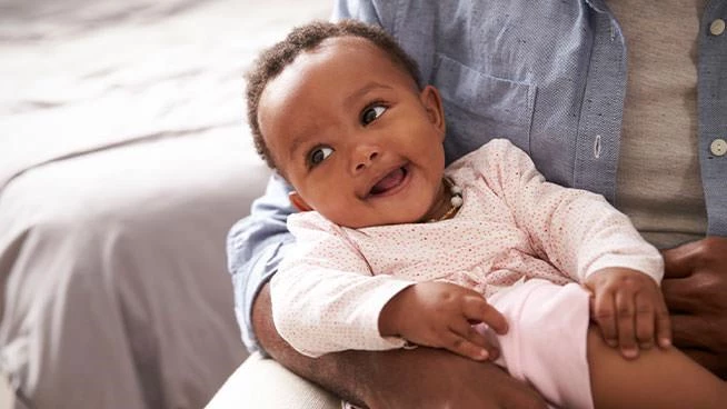 Happy baby looking off to the side while laying in parent's arms