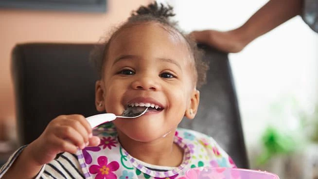 Niña sonriendo mientras come comida