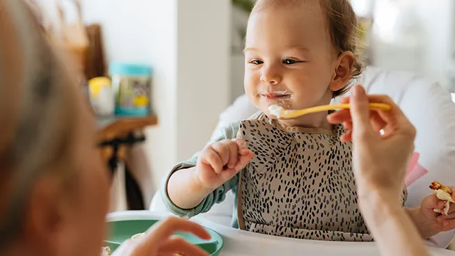 Mom feeding little girl food with a spoon