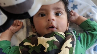 Baby in camo shirt laying on the floor