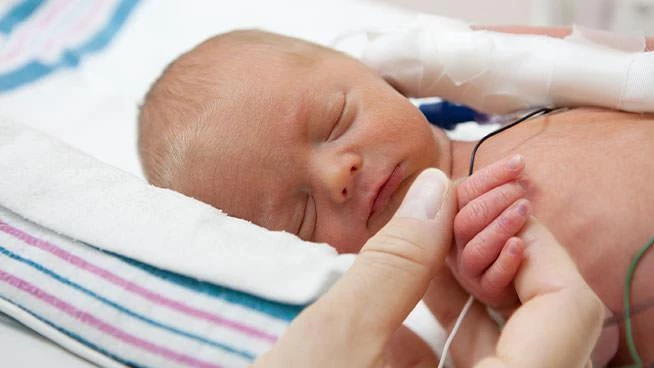 Mom holding the hand of her sleeping preemie