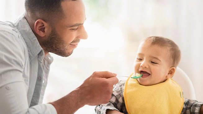 Papá alimentando a un bebé feliz