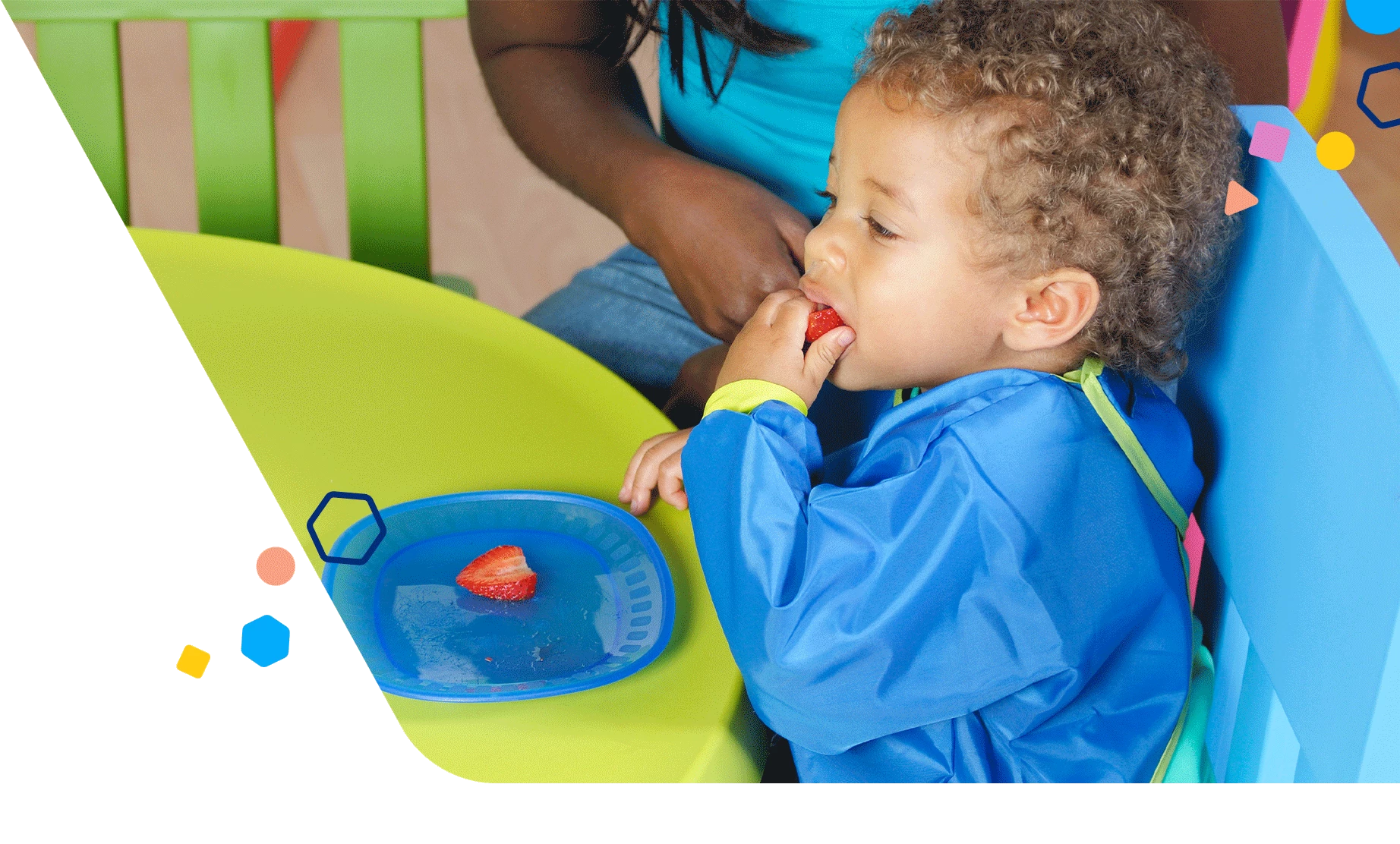 Toddler boy eating strawberries with his mom sitting by him