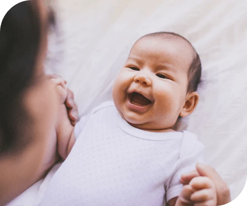 Laughing baby holding hands of their mom