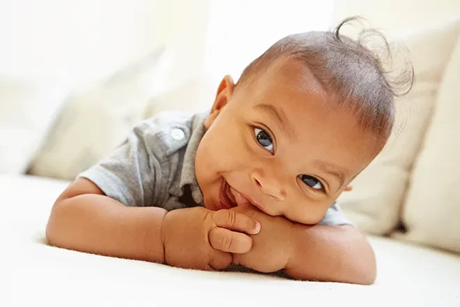 Newborn smiling as they chew their thumb