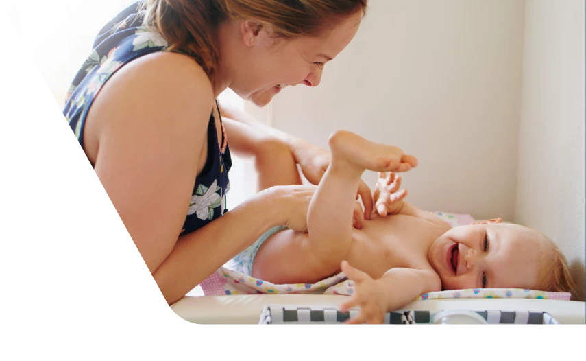 Smiling mom changing happy baby's diaper