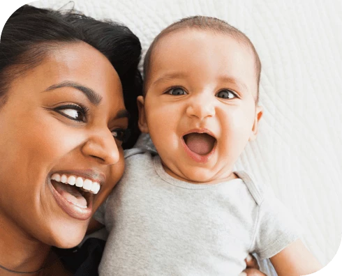 Madre y bebé acostados, ambos sonriendo