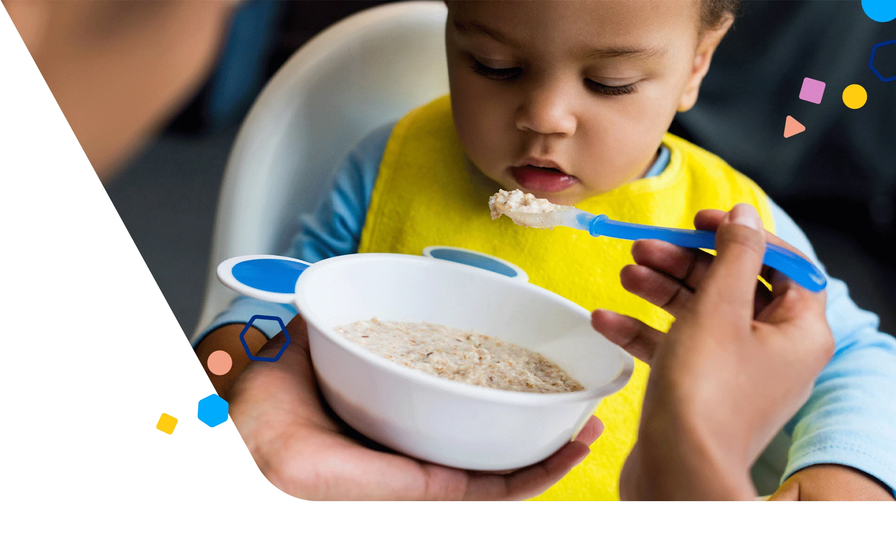 Mom spoon-feeding toddler son in high chair