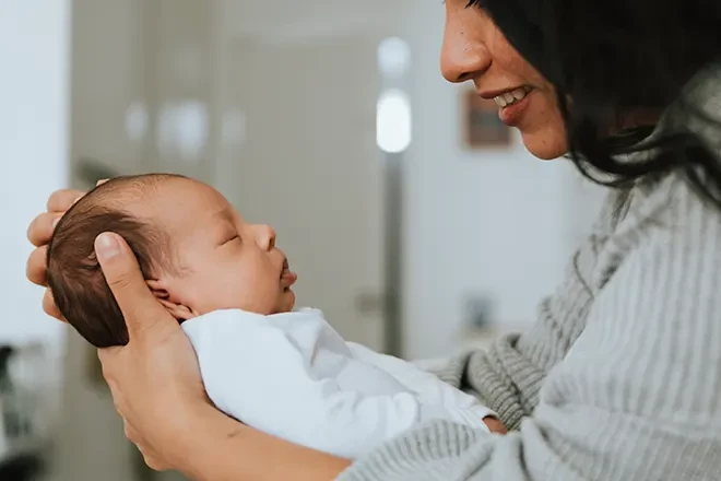 Smiling mom holding sleeping newborn