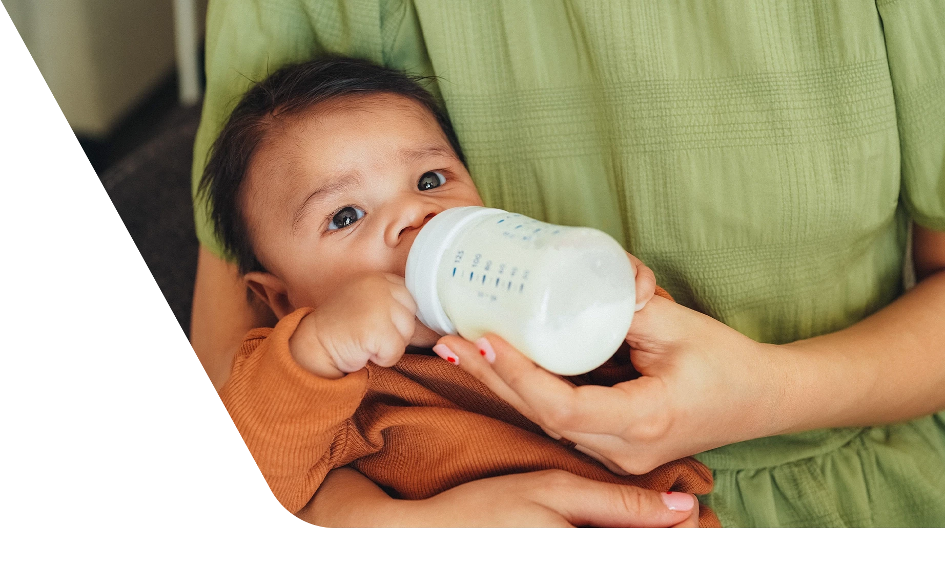 Baby drinking bottle in mother's arms