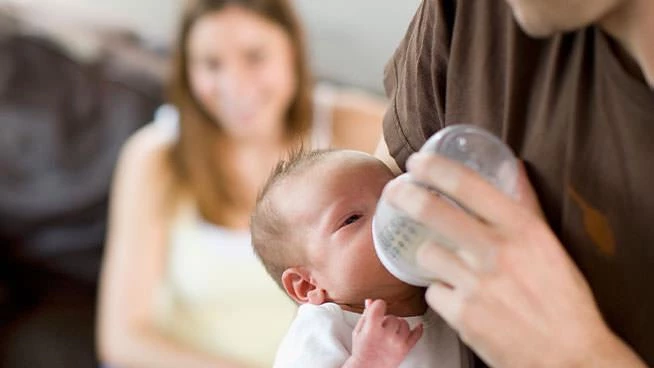 Papá alimentando con biberón a un bebé recién nacido