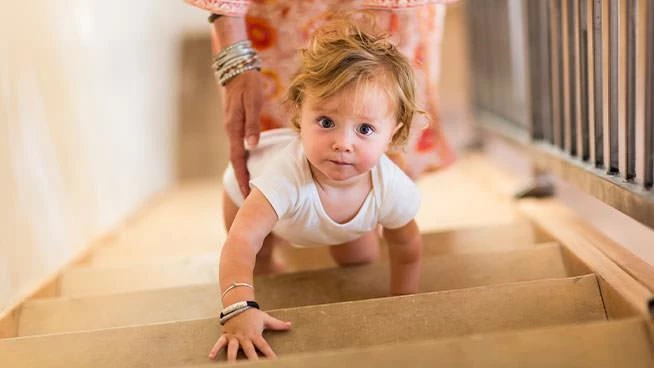 Un niño pequeño subiendo las escaleras con su mamá detrás de él