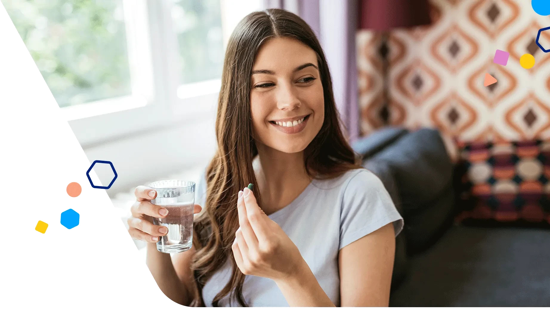 Smiling woman holding a glass of water and a vitamin