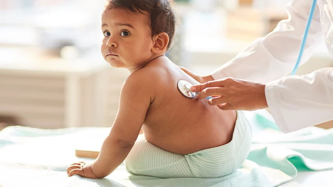 Doctor holding stethoscope to babys back