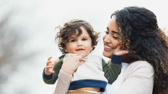 Mamá sonriente sosteniendo a su niño pequeño