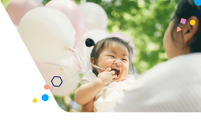 Niño feliz sosteniendo globos con su mamá