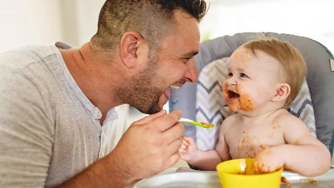 Papá alimenta felizmente a su pequeño