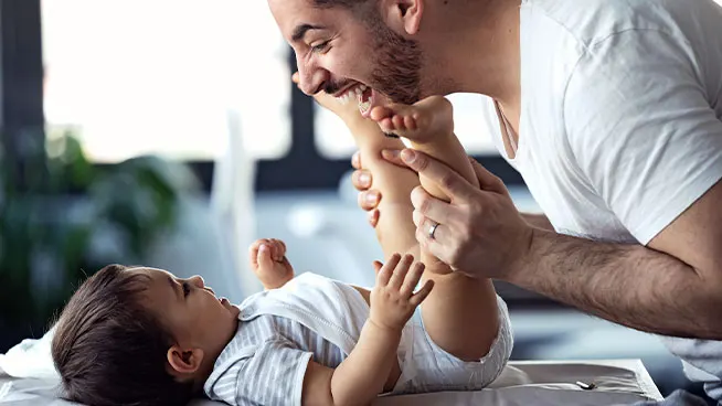 Dad playing peekaboo with newborn