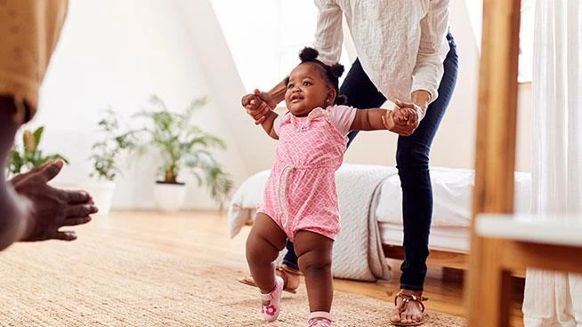 Padres ayudando a la niña a caminar en la sala de estar