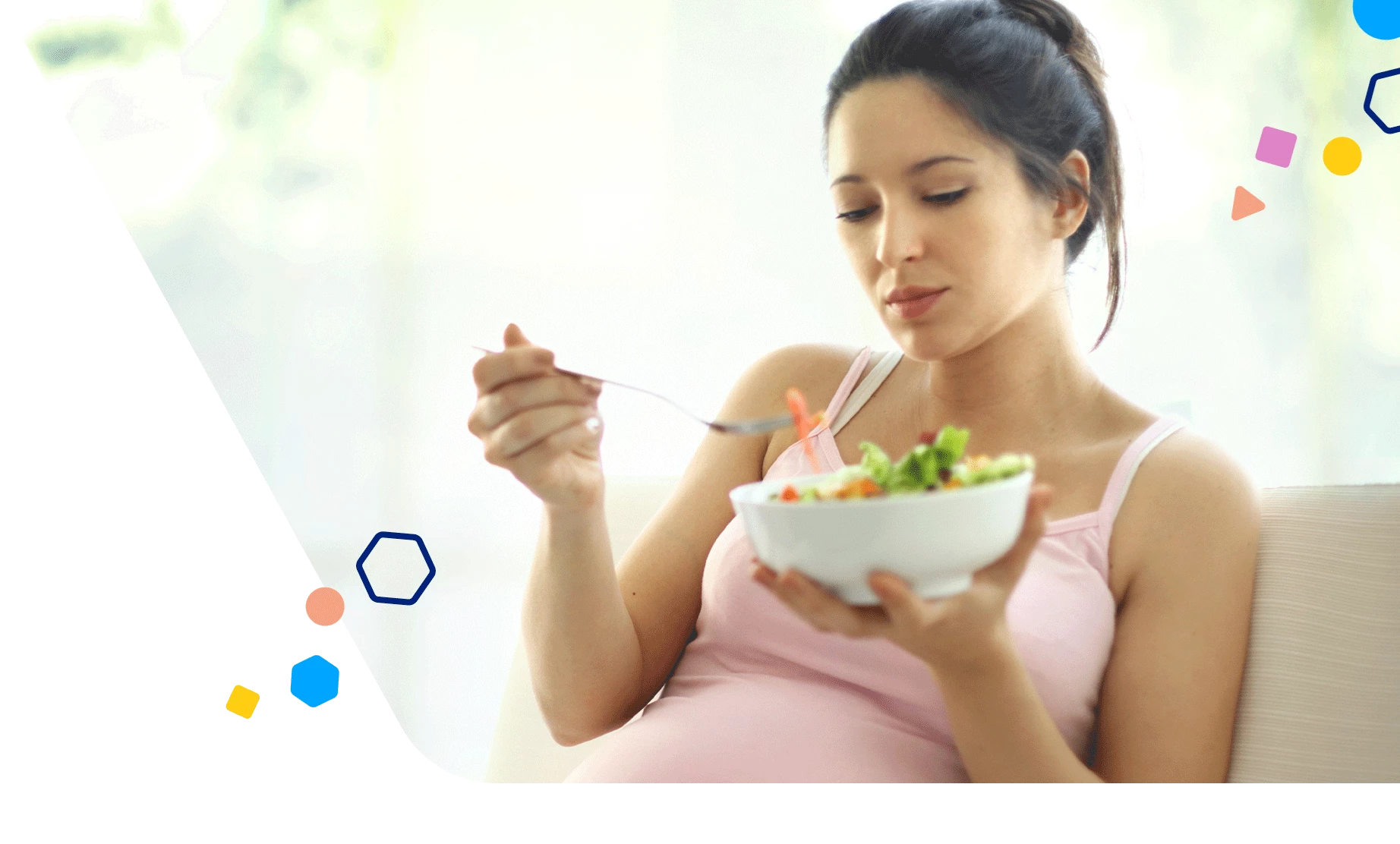 Pregnant mom sitting on the couch eating a salad