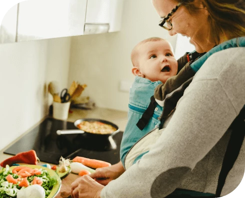 Smiling mom holding happy baby in a carrier