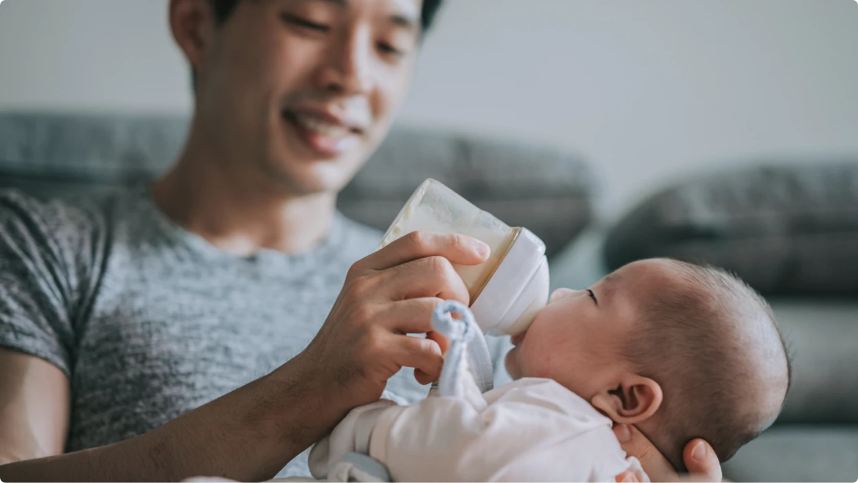 Smiling dad feeding baby a bottle