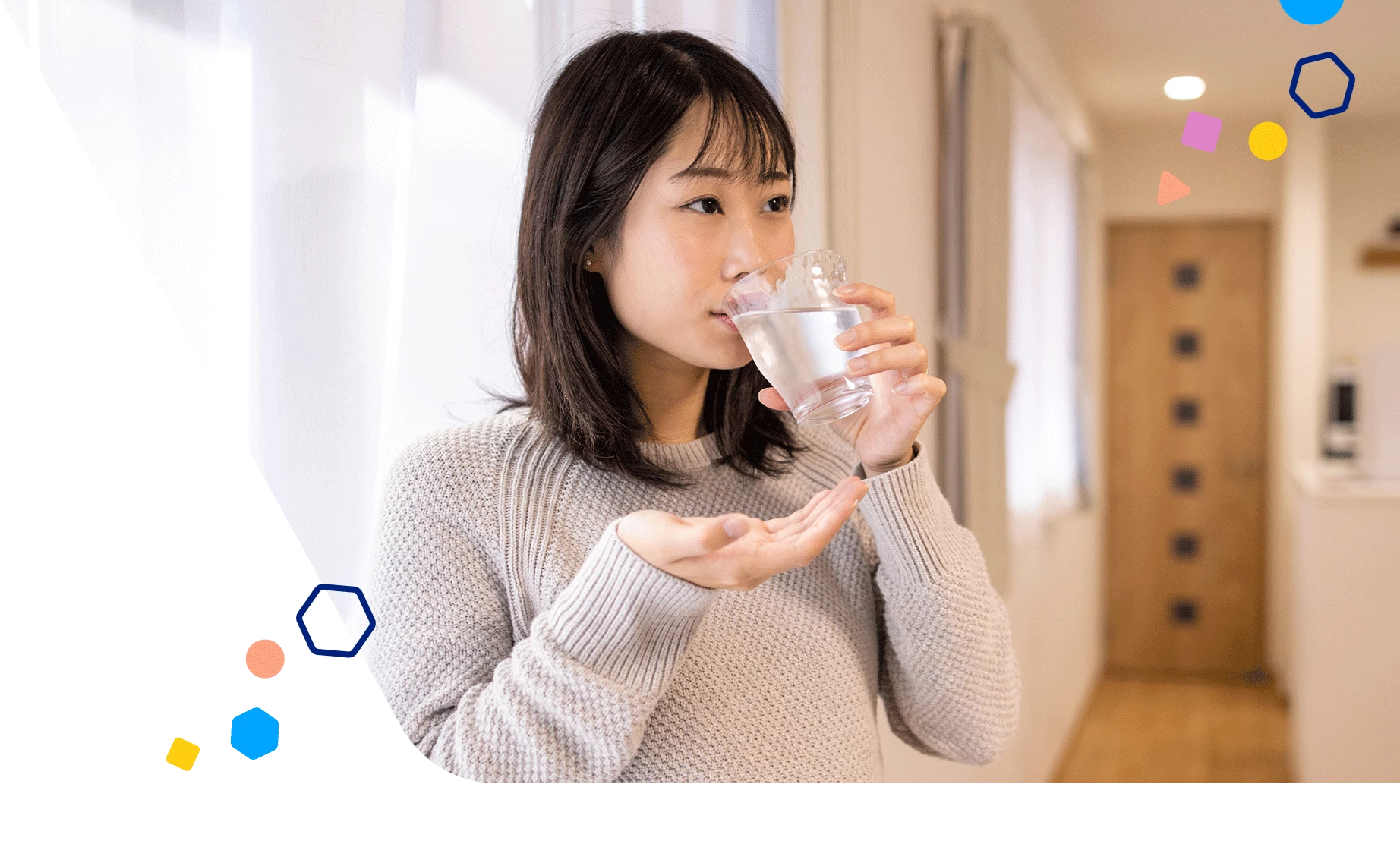 Pregnant woman drinking a glass of water and holding a vitamin