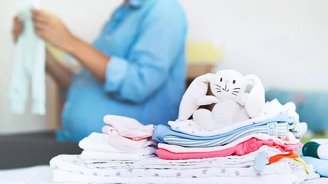 Pregnant mom packing baby clothes