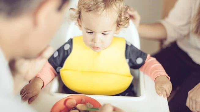 Dad feeding toddler in a high chair