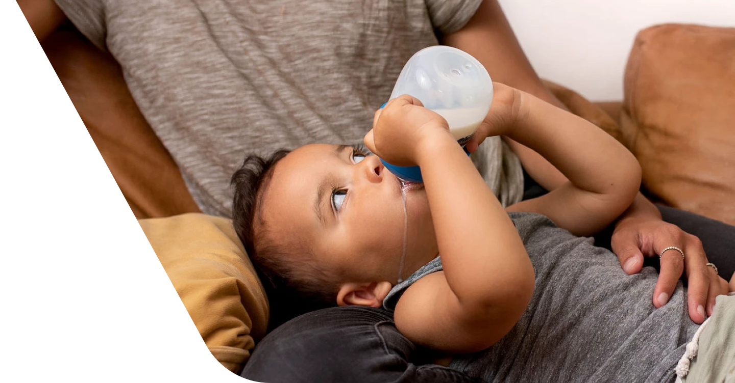 Niño acostado con sus padres y bebiendo una taza de leche