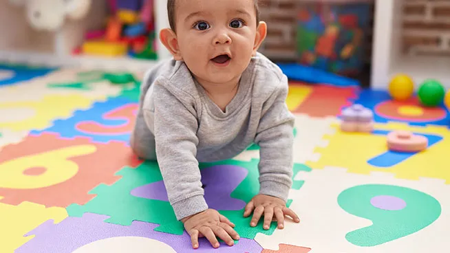 Baby crawling on multi-colored puzzle mat