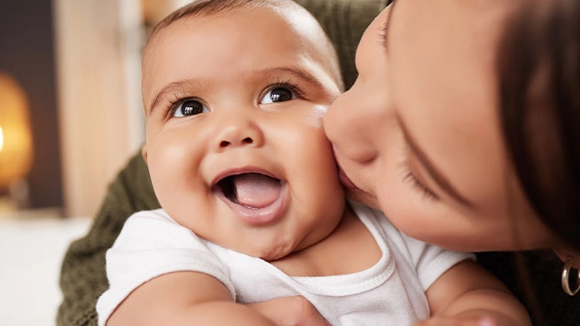 mamá besando la mejilla de su bebé